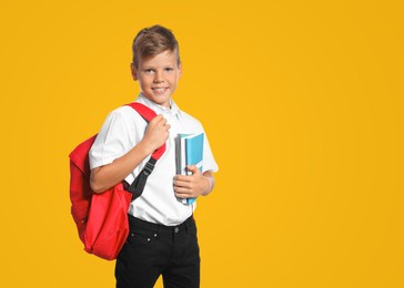 Image of Little boy with backpack and notebooks on yellow background. Back to school