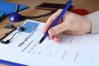 Woman filling visa application form for immigration to European Union at table, closeup