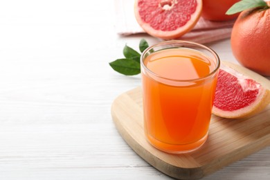 Tasty freshly made grapefruit juice on white wooden table. Space for text