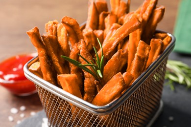 Frying basket with sweet potato fries on table, closeup