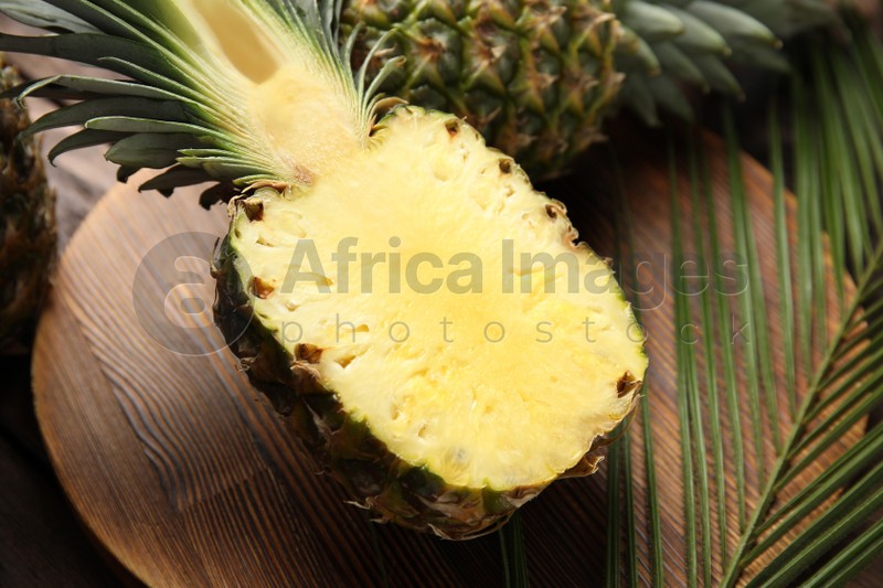 Photo of Half of pineapple on wooden board, closeup