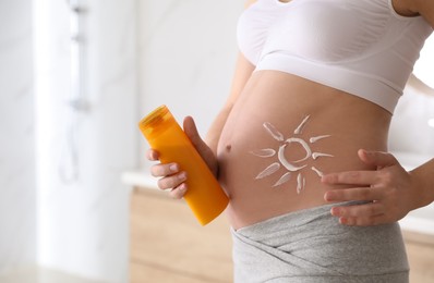Young pregnant woman with sun protection cream indoors, closeup. Space for text