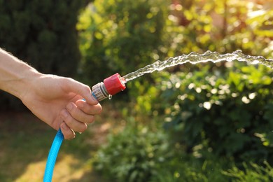 Man pouring water from hose in garden, closeup