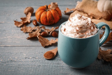 Photo of Delicious pumpkin latte on grey wooden table, closeup