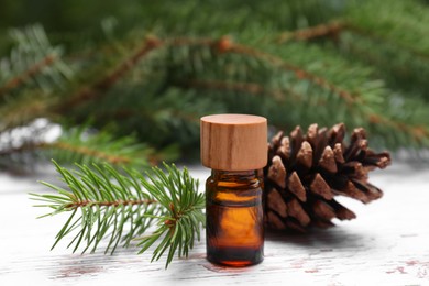 Bottle of pine essential oil, conifer tree branches and cone on white wooden table, closeup