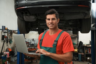 Photo of Mechanic with laptop for car diagnostic at automobile repair shop