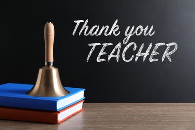 Image of School bell and books on wooden table near blackboard with phrase Thank You Teacher