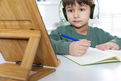 Cute little boy with tablet studying online at home, focus on hand. E-learning