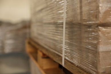 Stacks of merchandise wrapped in stretch film on wooden pallet, closeup