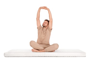 Man stretching on soft mattress against white background