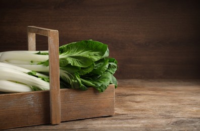 Fresh green pak choy cabbages in crate on wooden table. Space for text