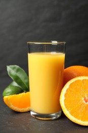 Photo of Glass of orange juice and fresh fruits on grey table