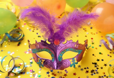 Beautiful purple carnival mask and party decor on yellow background
