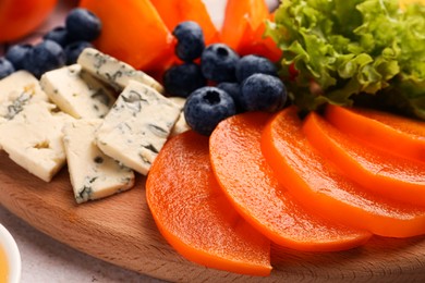 Photo of Delicious persimmon, blue cheese and blueberries on table, closeup