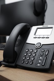 Stationary phone on wooden desk in office. Hotline service