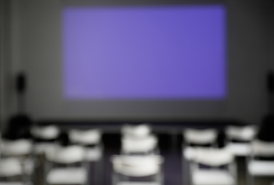 Blurred view of empty conference room with chairs and projector screen