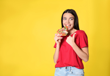 Emotional woman eating tasty pizza on yellow background