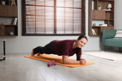 Overweight woman doing plank exercise at home