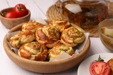 Photo of Fresh delicious puff pastry with tasty filling and tomatoes on white wooden table, closeup