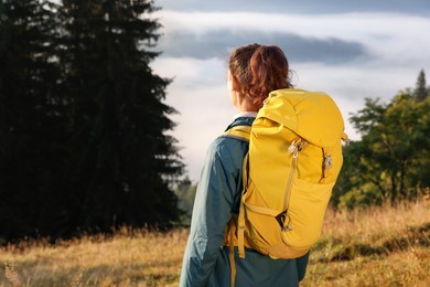 Tourist with backpack in nature on sunny day, back view. Space for text