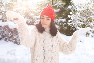 Happy young woman playing with snow outdoors. Winter vacation