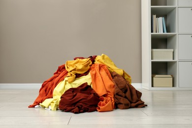 Pile of dirty clothes on floor near light brown wall indoors