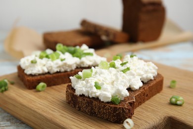 Photo of Bread with cottage cheese and green onion on table, closeup