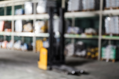 Blurred view of modern electric pallet truck in wholesale warehouse