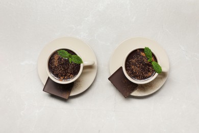 Cups of delicious hot chocolate with fresh mint on grey table, flat lay