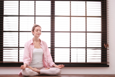 Young woman meditating at home, space for text. Zen concept