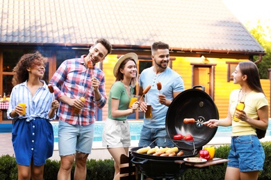 Photo of Group of friends with grilled sausages at barbecue party outdoors
