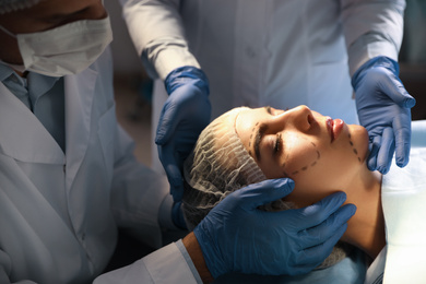 Doctor and nurse preparing female patient for cosmetic surgery in clinic