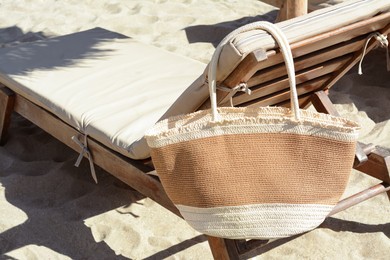 Straw bag on wooden sunbed outdoors. Beach accessory