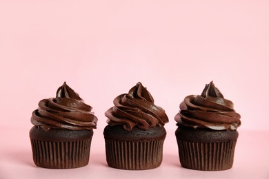 Delicious chocolate cupcakes with cream on pink background. Space for text