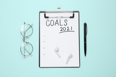 Clipboard with inscription Goals 2021, new year aims. Objects on turquoise background, flat lay