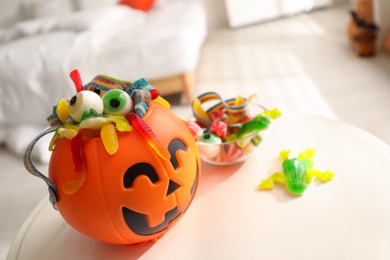 Halloween trick or treat bucket and many different sweets on white table indoors