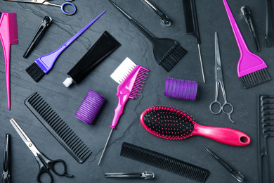 Professional tools for hair dyeing on black stone background, flat lay