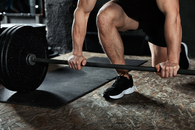 Man lifting barbell in modern gym, closeup