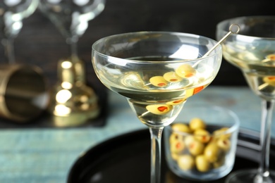 Glass of Classic Dry Martini with olives on wooden table, closeup