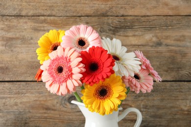 Bouquet of beautiful colorful gerbera flowers in vase on wooden background