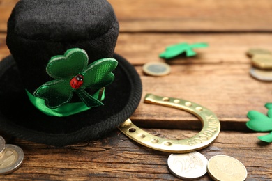 Leprechaun hat, decorative clover leaves, horseshoe and coins on wooden table, closeup view with space for text. St Patrick's Day celebration
