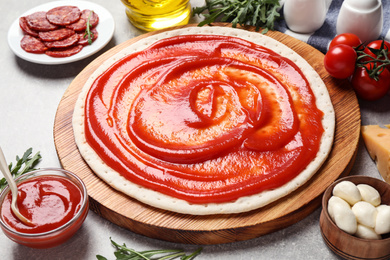 Base and fresh ingredients for pepperoni pizza on light grey table