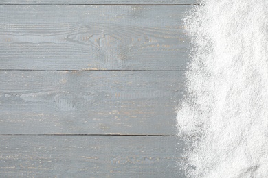 Artificial snow on light grey wooden background, top view with space for text. Christmas decor