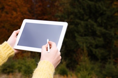 Woman drawing with graphic tablet near forest in autumn, closeup