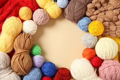 Frame of colorful woolen yarns on beige background, flat lay. Space for text