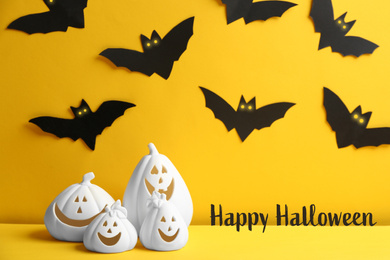 Happy Halloween greeting card design. Jack-o-Lantern candle holders and paper bats on yellow background
