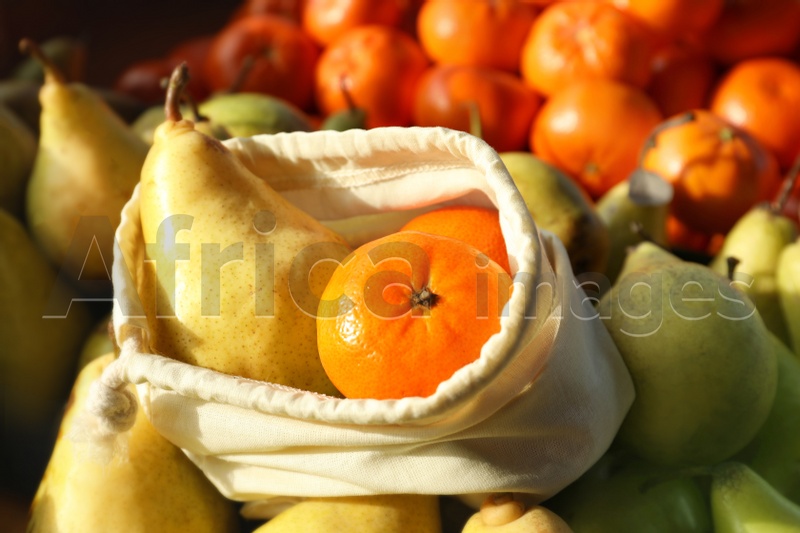 Photo of Cotton eco bag with fruits on pears, closeup. Life without plastic