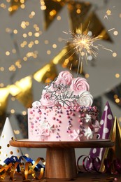 Beautiful birthday cake with burning sparkle and decor on wooden table