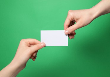 Photo of Women holding blank gift card on green background, closeup