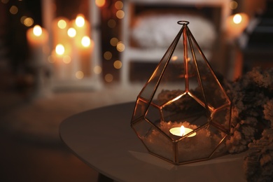 Photo of Stylish lantern with burning candle and Christmas decor on table indoors, space for text. Interior design